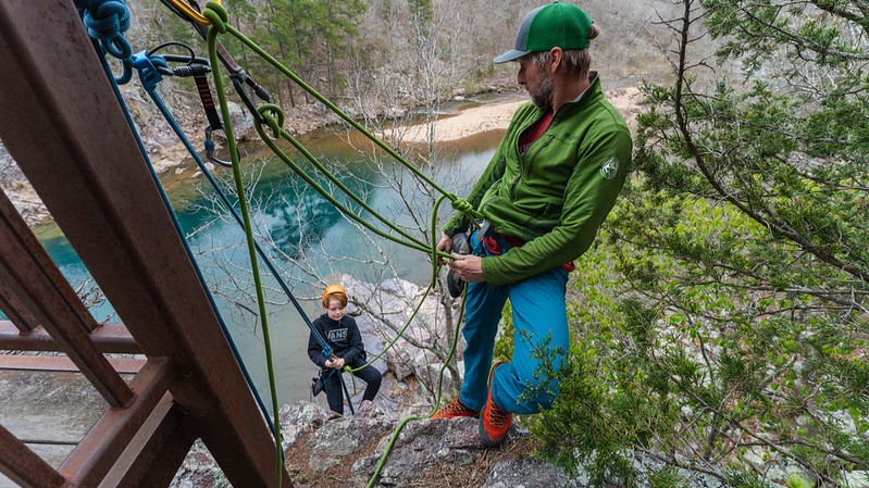 A dad and his son rappelling down a rocky hill